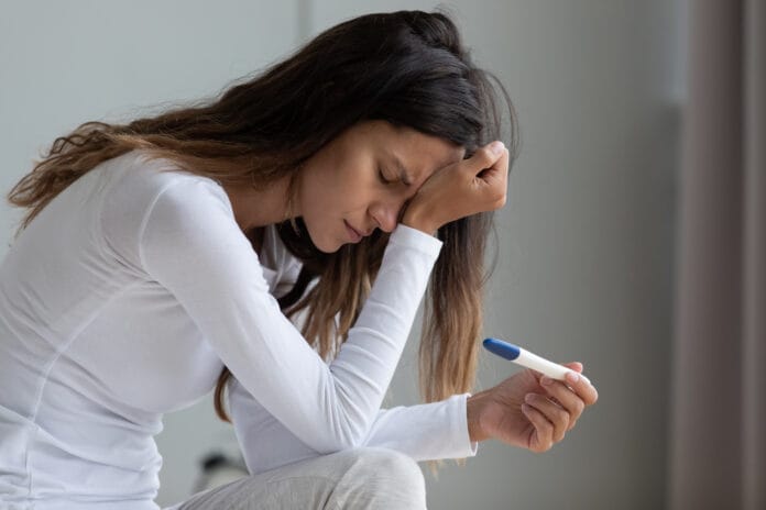Close,Up,Unhappy,Upset,Woman,Holding,Pregnancy,Test,,Touching,Forehead,